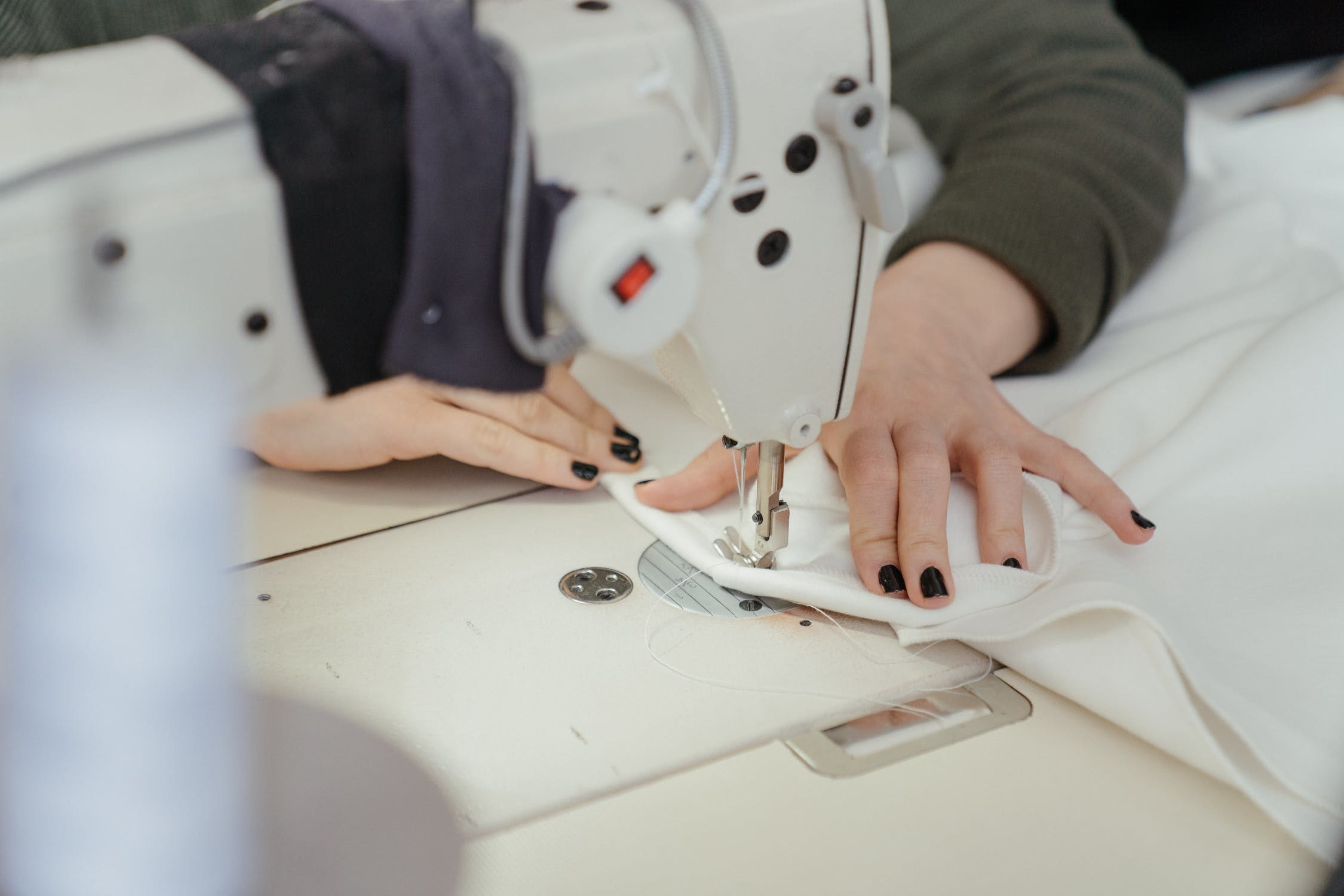 Handen aan het werk achter de naaimachine in het atelier